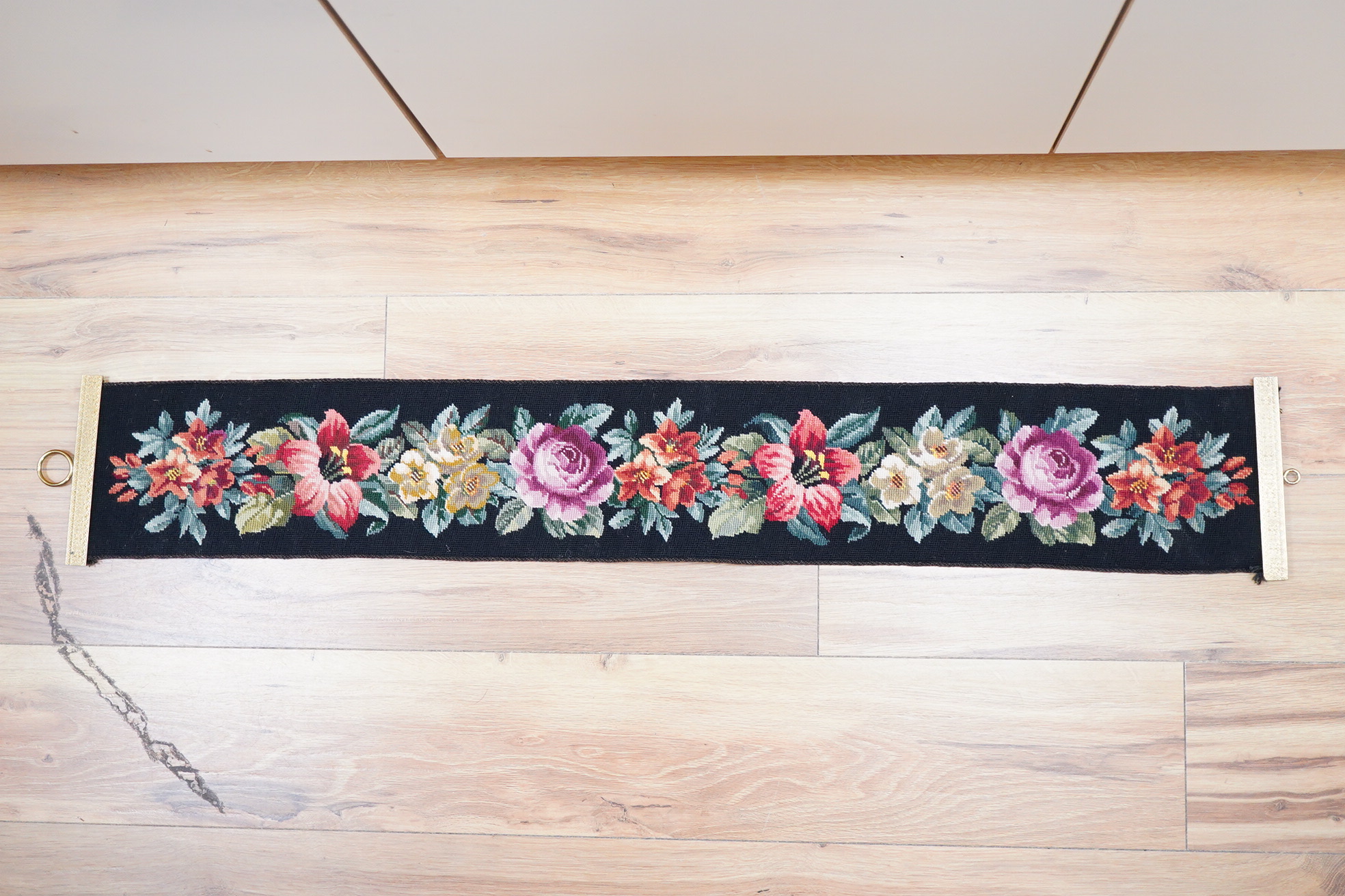 A framed 19th century woolwork embroidery of a bird, a floral wool bell pull with gilt mounts and a large maple frame